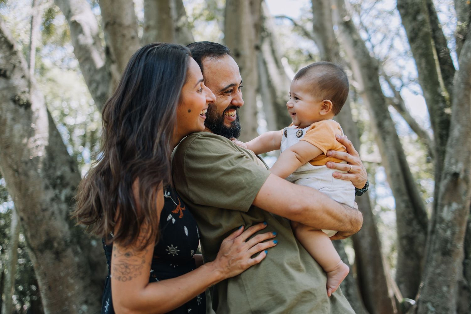 Family playing and laughing together in a wooded forest setting.