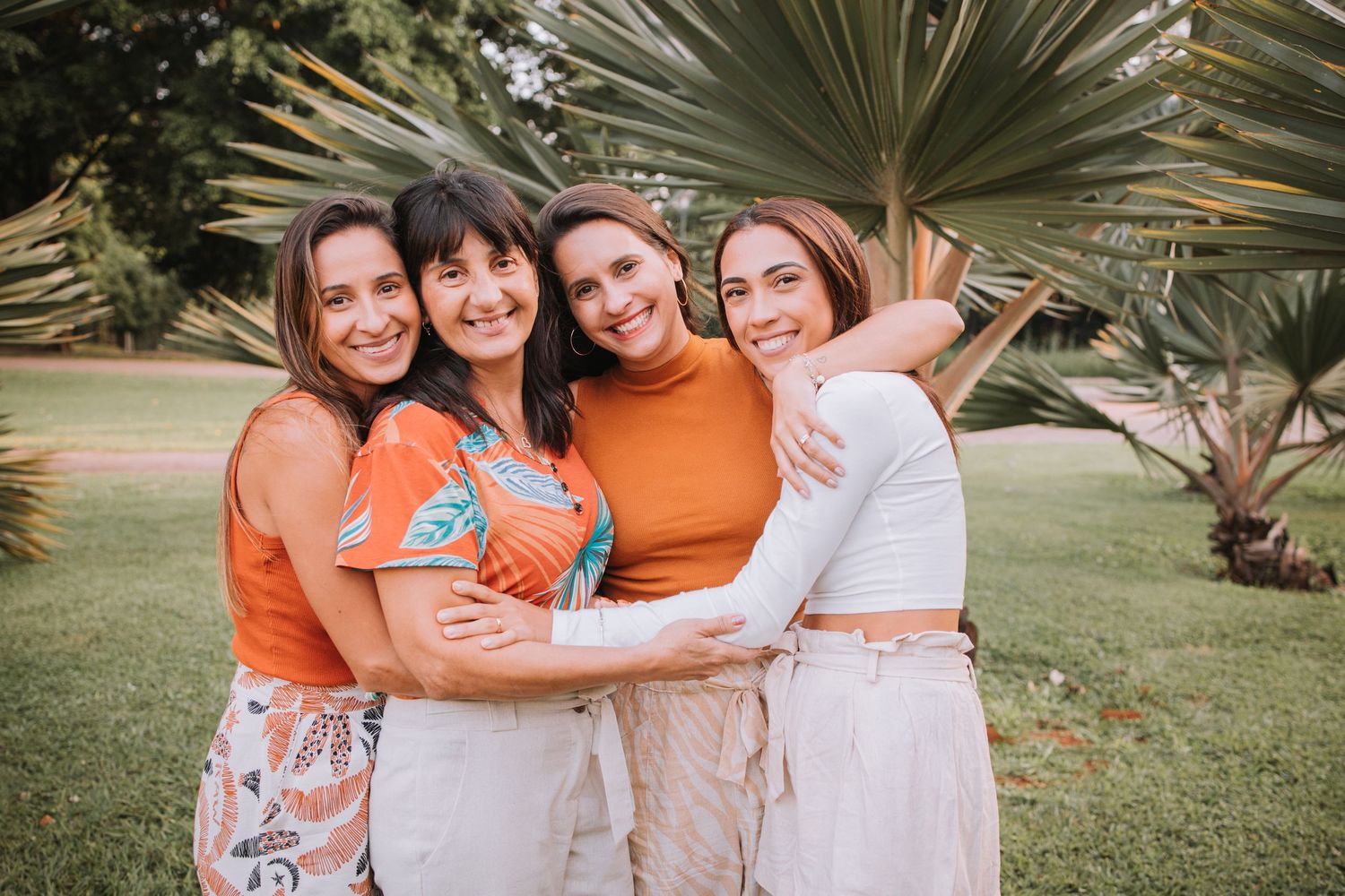 Happy group embrace during sunset photoshoot with palm trees in background.
