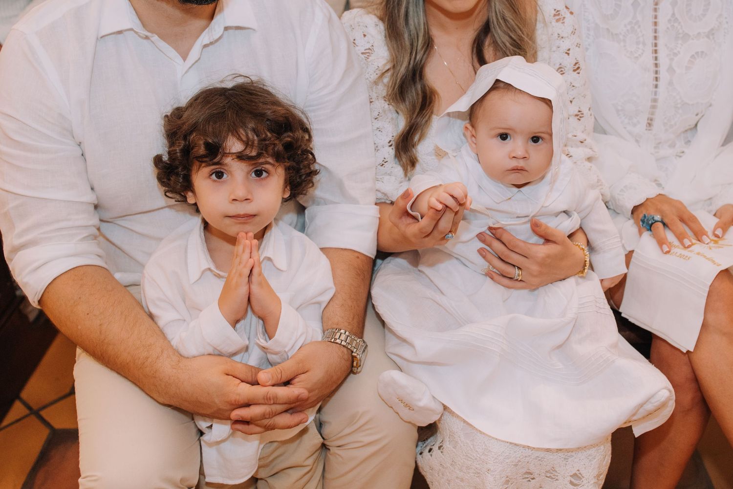 Family members in white outfits pose together during a special event.