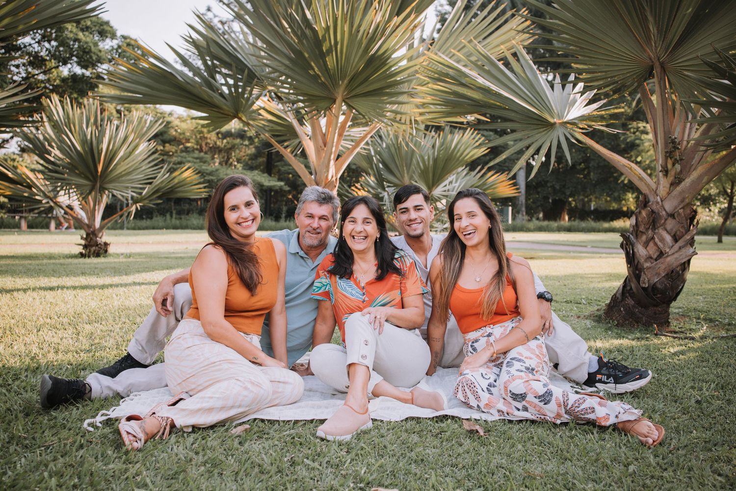 Family group lounging on blanket for casual outdoor photo session.