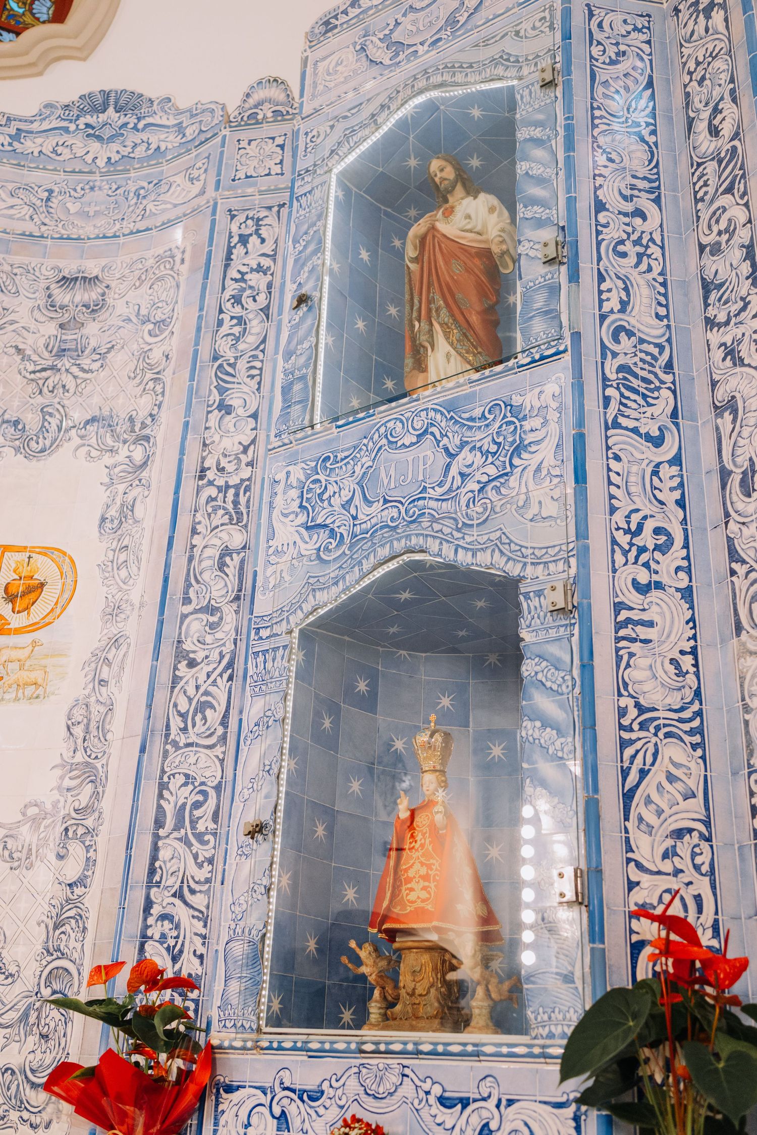 Blue and white azulejo tiled church wall with religious statues of Jesus and Virgin Mary in ornate niches.