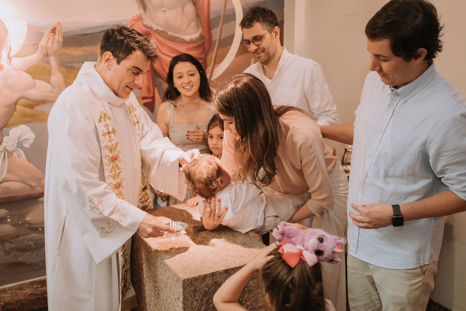 A religious blessing ceremony takes place in a church with participants gathered in prayer.