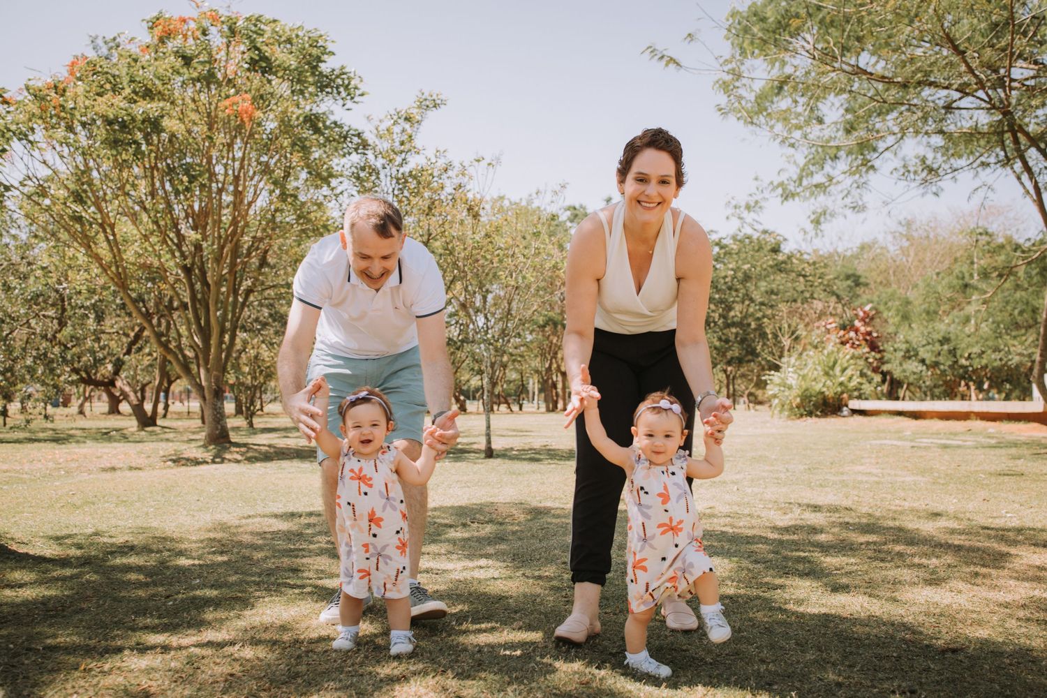 A cheerful outdoor family photoshoot in a park with trees in the background.