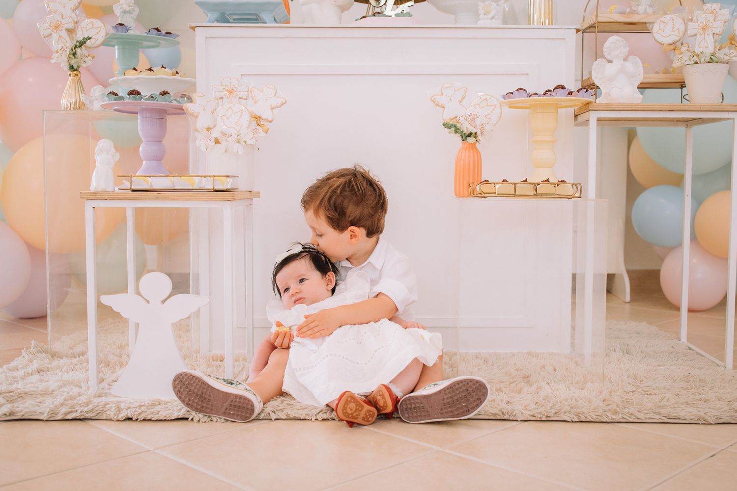Child lying on floor in white room decorated with pastel balloons and shelving.
