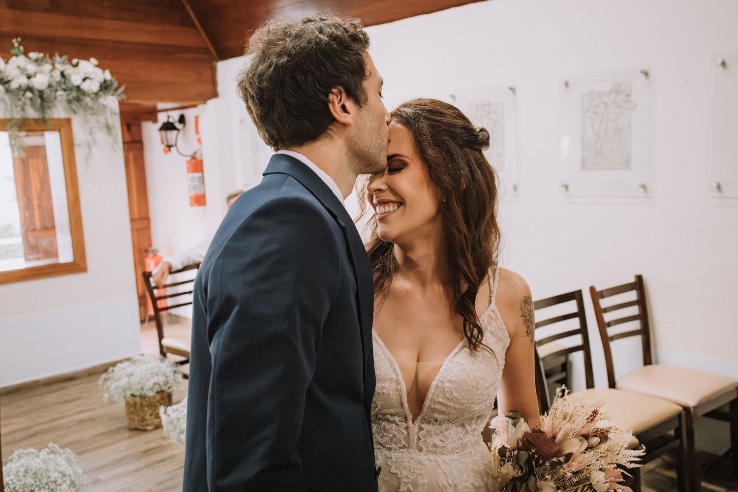 A couple shares an intimate moment in a rustic indoor venue with wooden accents and floral decorations.