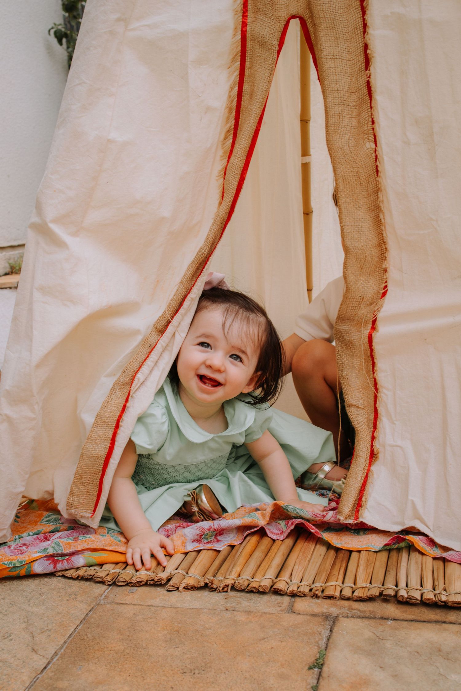 A small child peeks playfully from beneath a light-colored curtain in a series of four progressive shots.