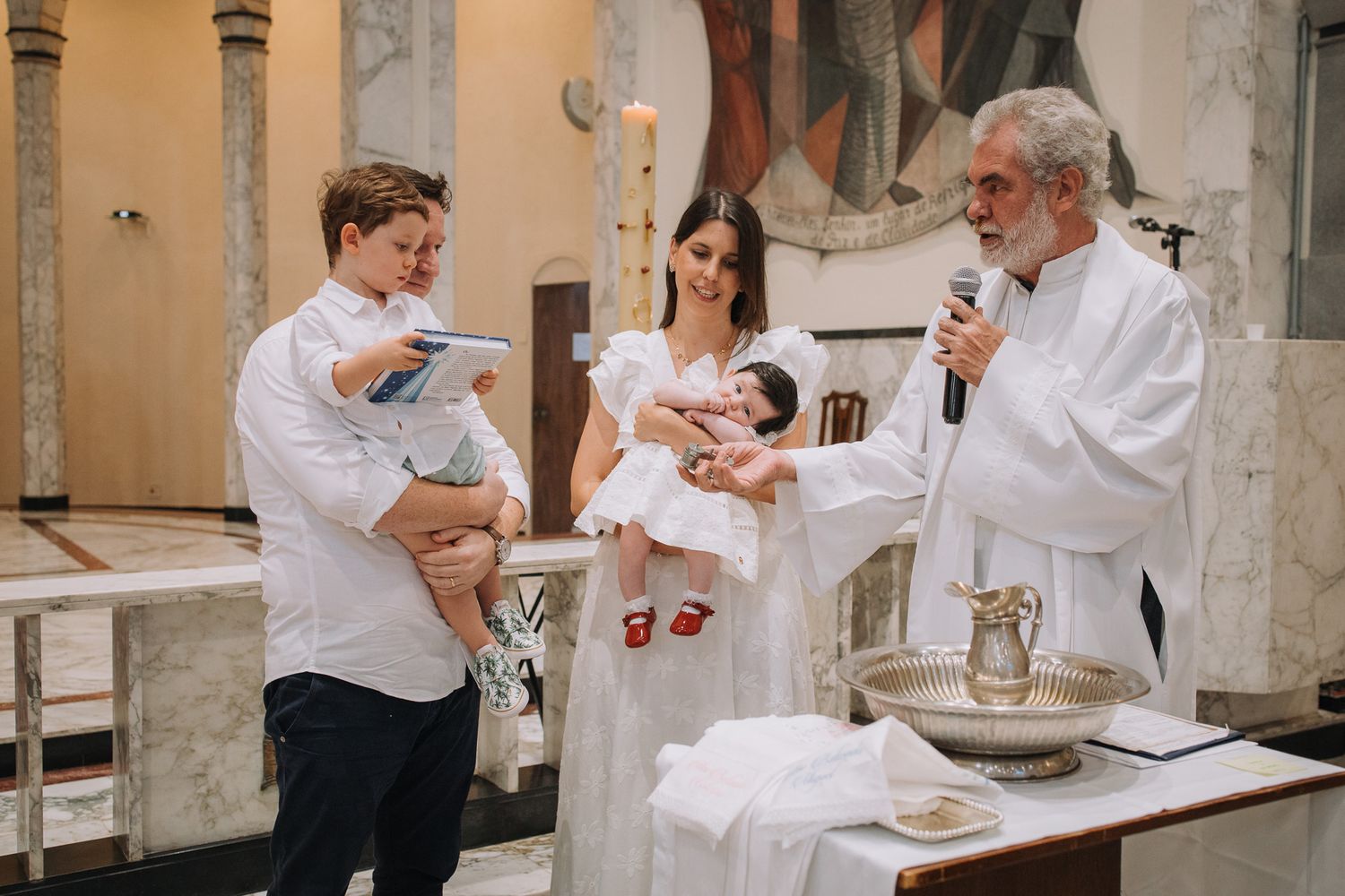 A religious ceremony takes place at a church altar with clergy and family members.