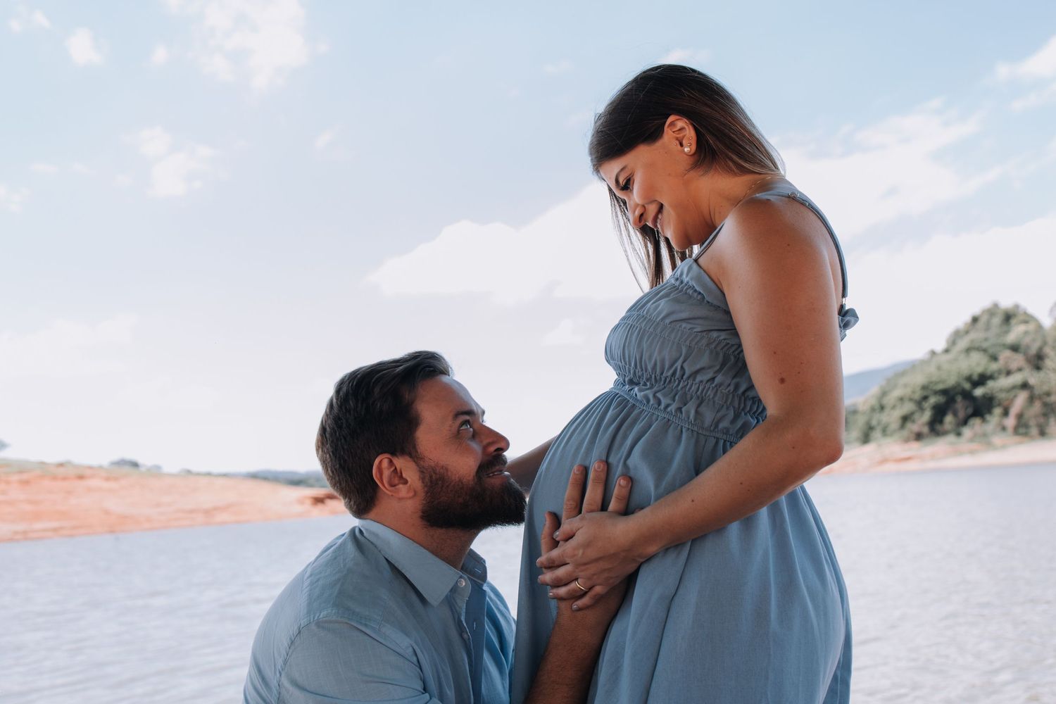 Intimate beachside maternity photo with blue sky background.