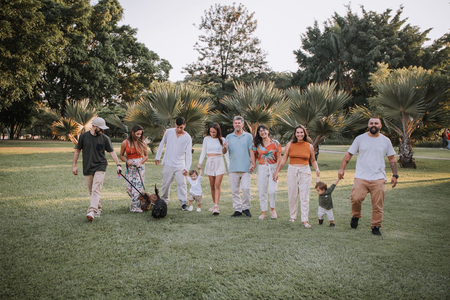 Group walking together on grass path with trees in background during sunset photoshoot.