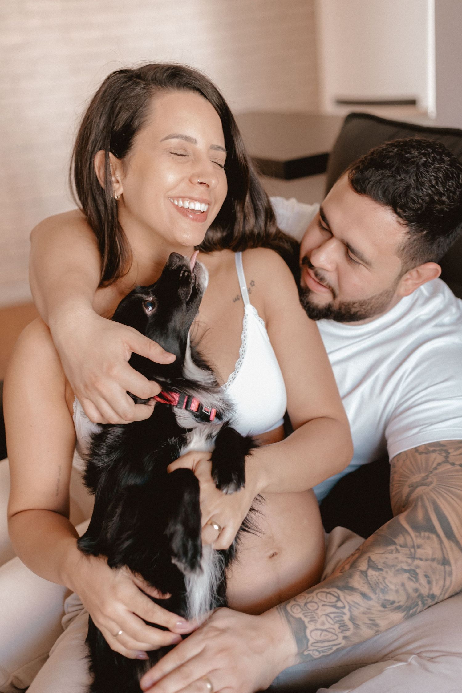 Couple sharing sweet moments with their black and white dog on bed.