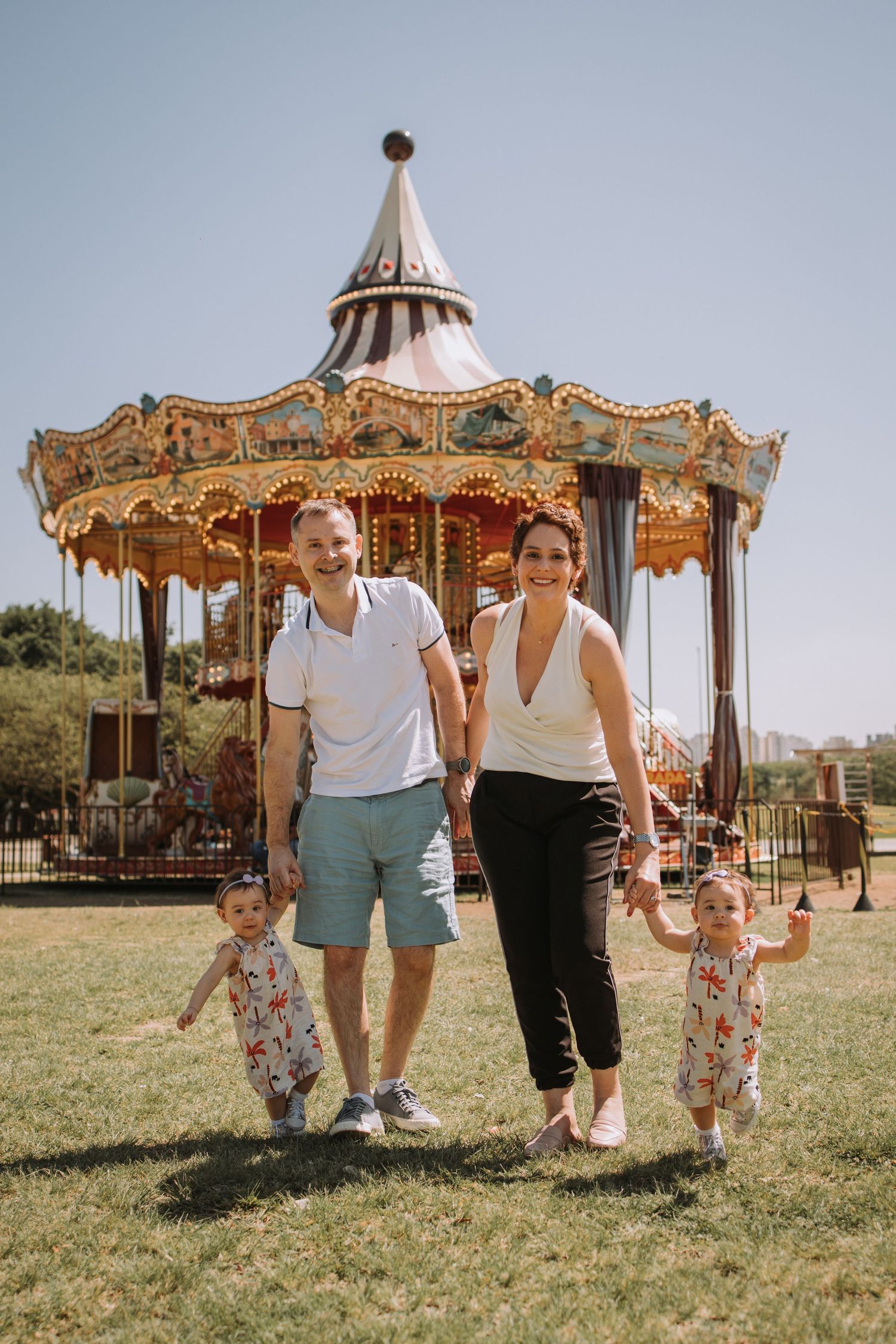 Family enjoying a sunny day at a vintage carousel in a park setting.