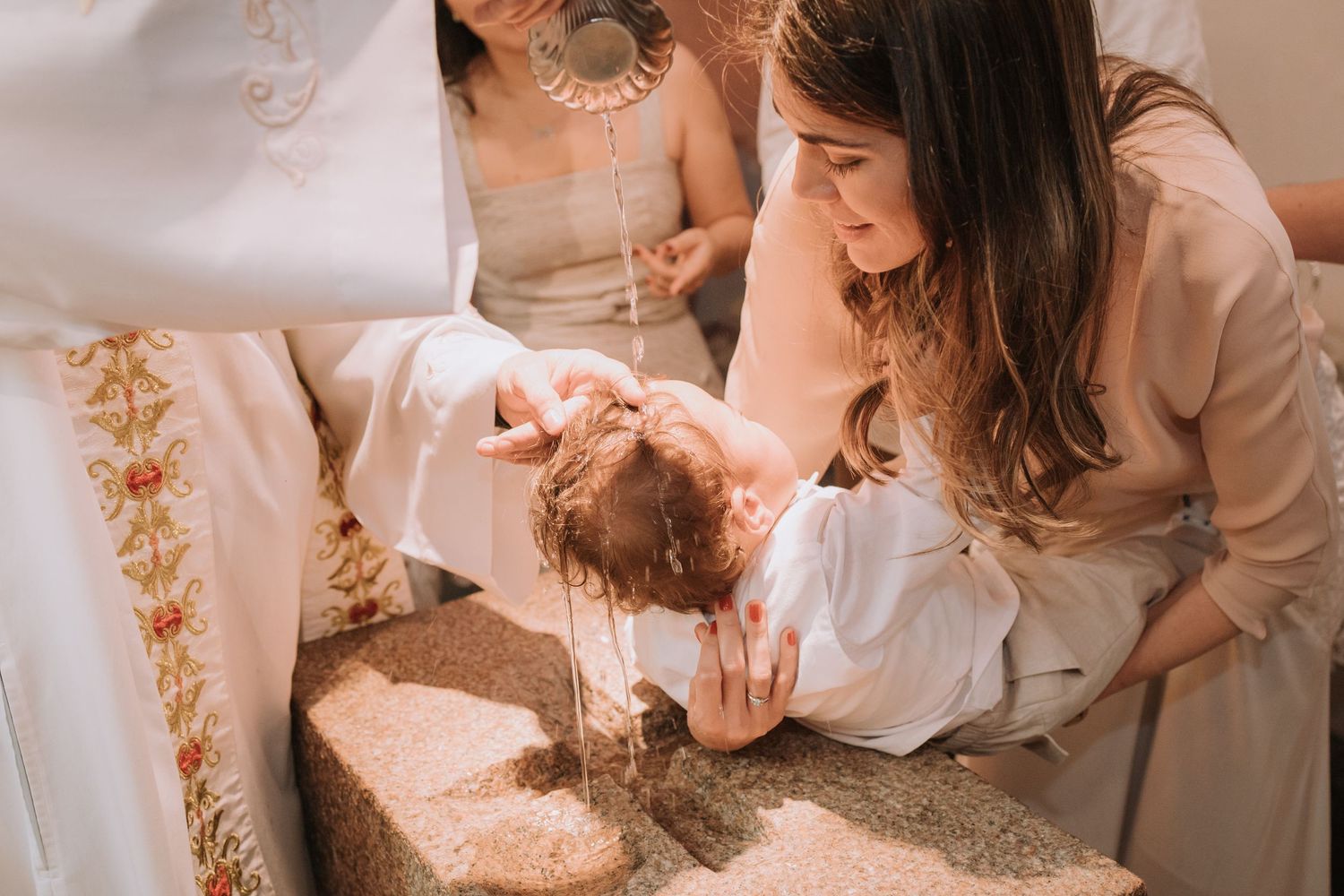 A baby receives baptismal water during a traditional church ceremony.