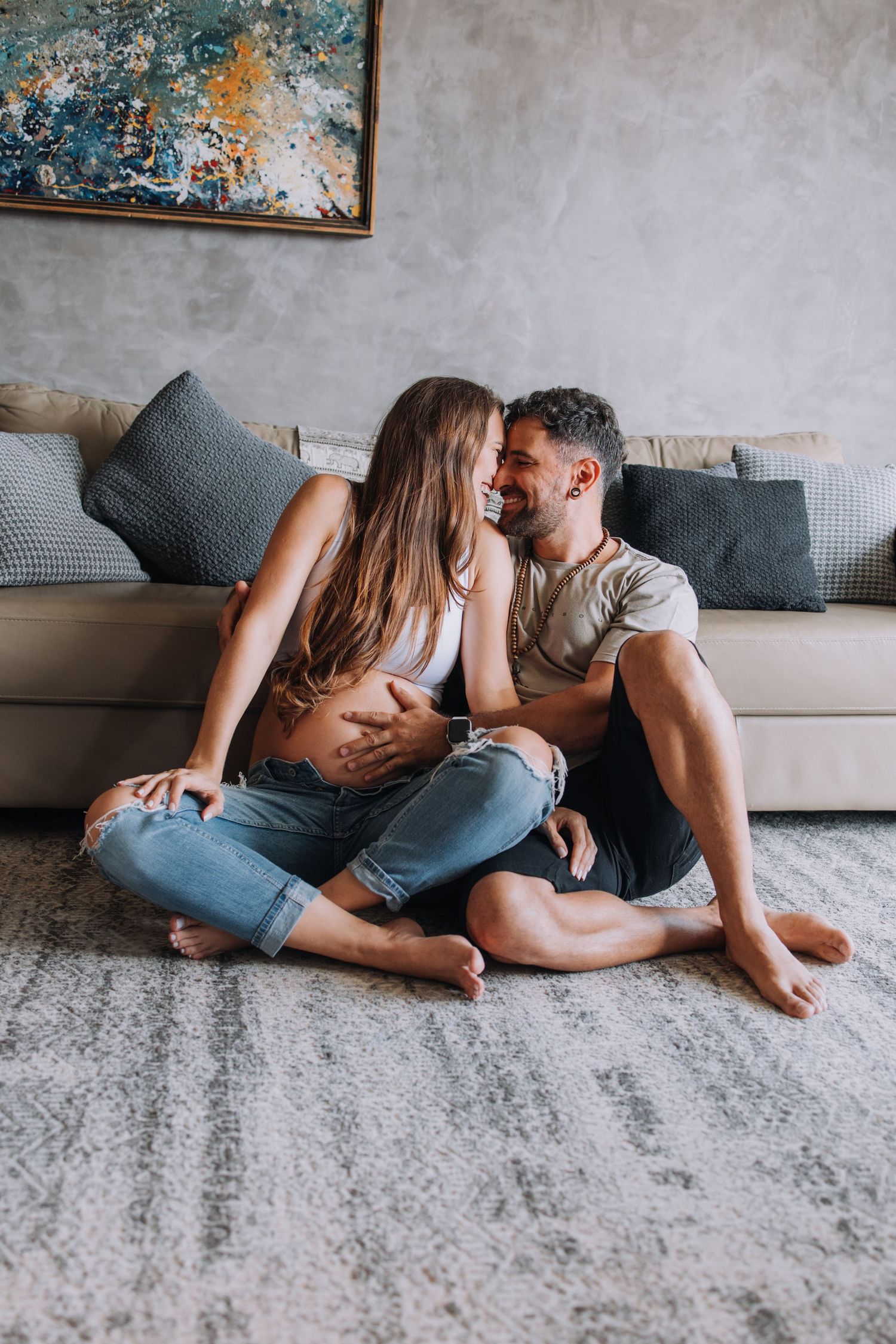 Intimate couple sharing tender moment on grey couch in modern living room.