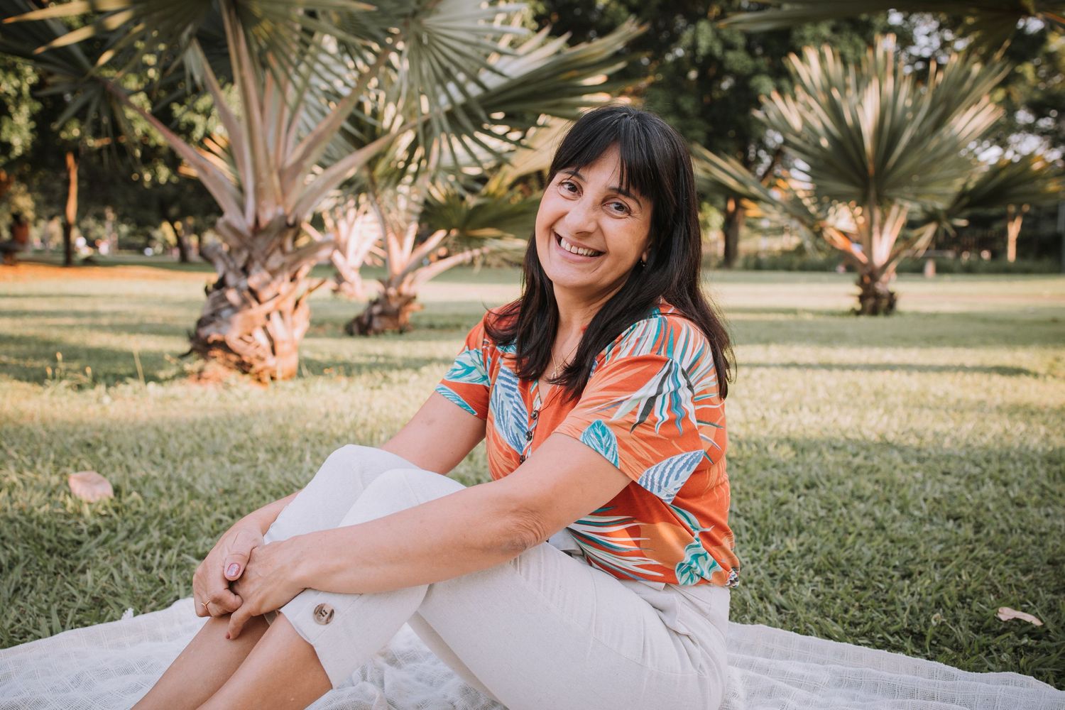 Family photo session in a tropical garden setting with palm trees and warm lighting at sunset.