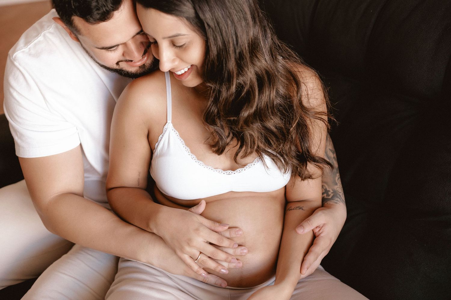 Tender maternity moment captured in warm tones with soft lighting.