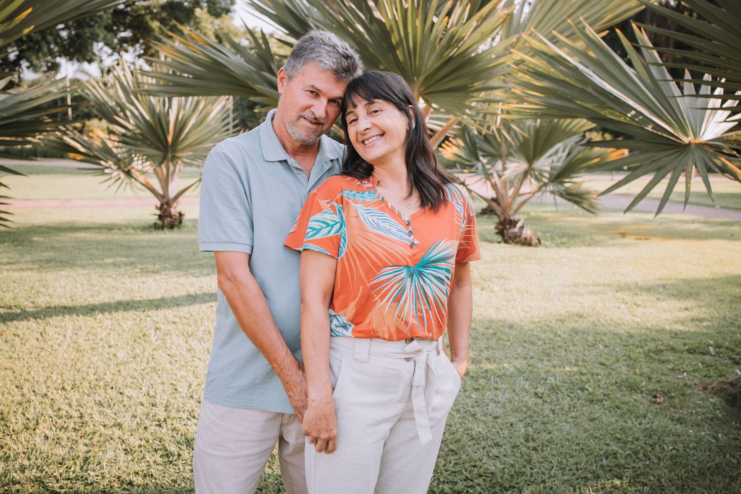 Couple in coordinating outfits sharing a tender moment under palm trees.