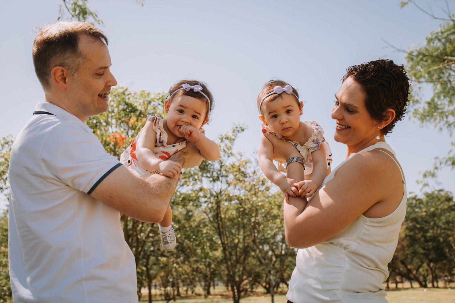 Family sharing joyful moment with baby in outdoor summer setting.