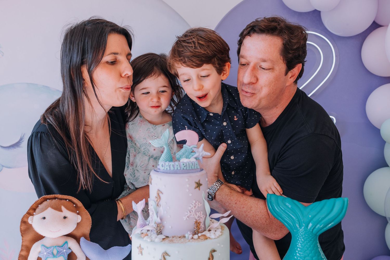 Family portrait session with pastel balloon arch and soft lighting indoors.