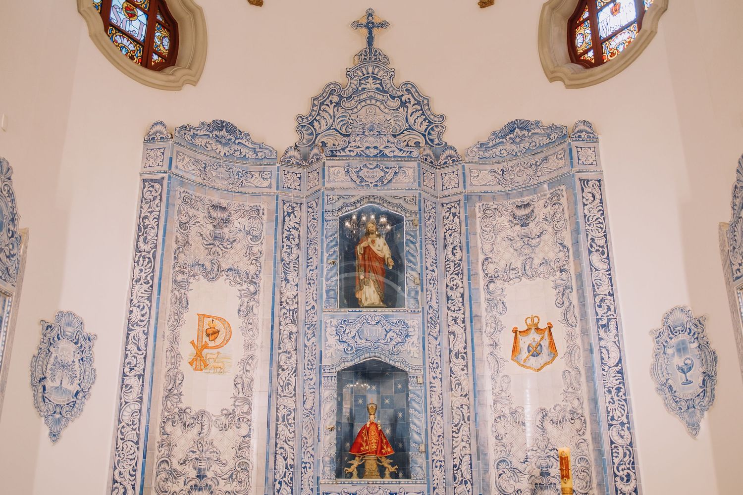 Ornate blue and white azulejo tile altar with religious statues and cross in a Portuguese baroque church.