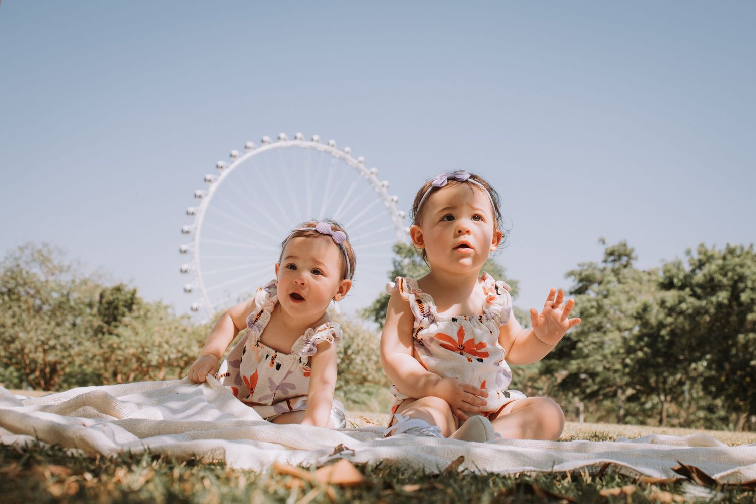 Children playing outdoors with a large ferris wheel visible in the background.