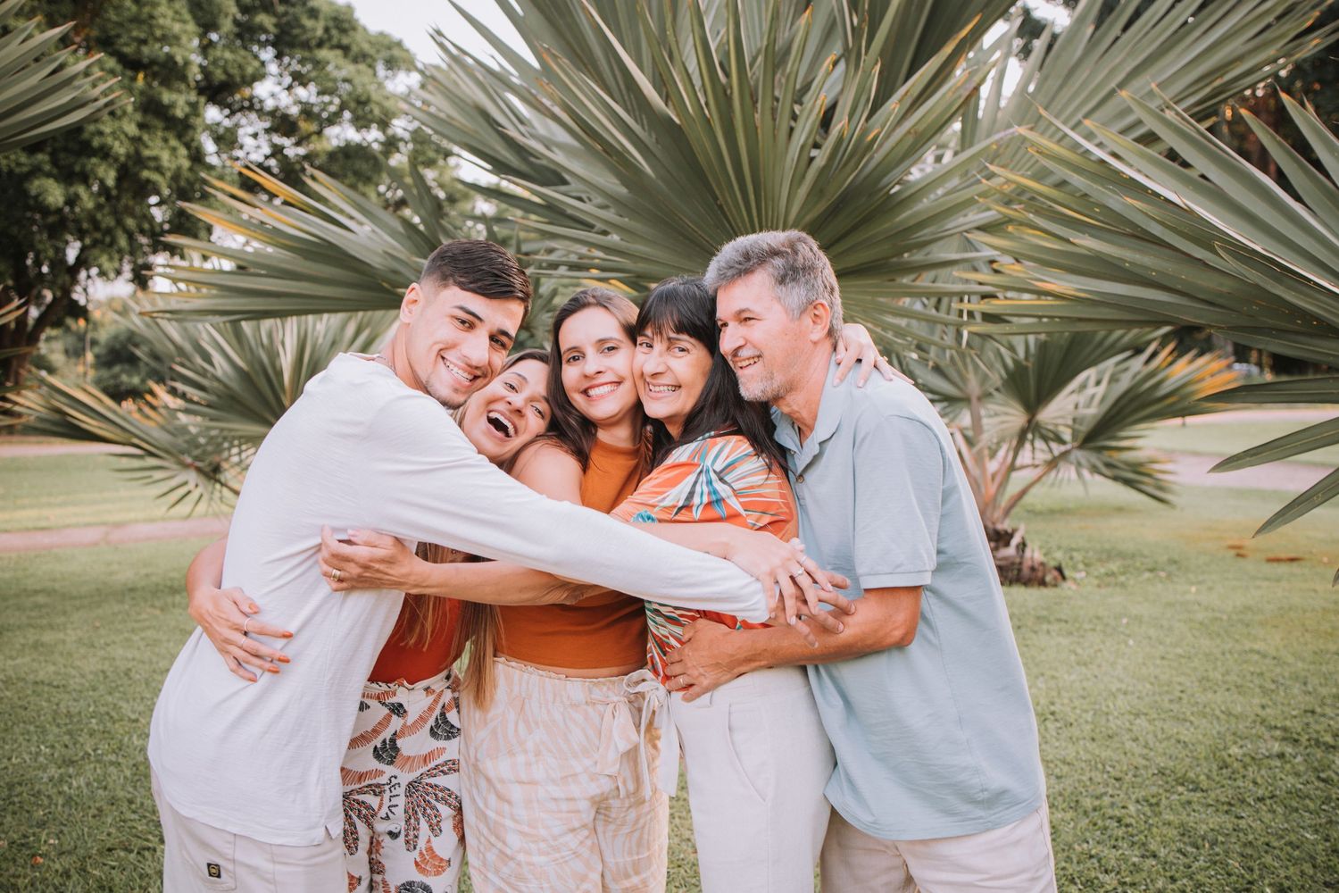 Intimate family group hug captured during outdoor photo session in park setting.