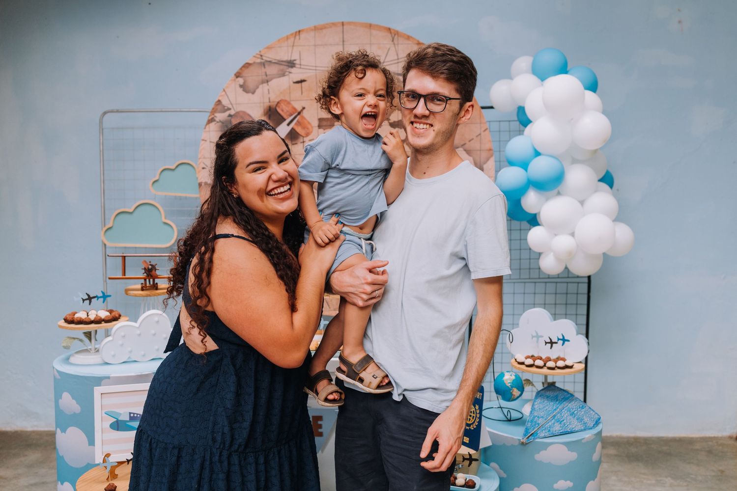 Family celebrating at baby birthday party with blue and white balloon decorations.