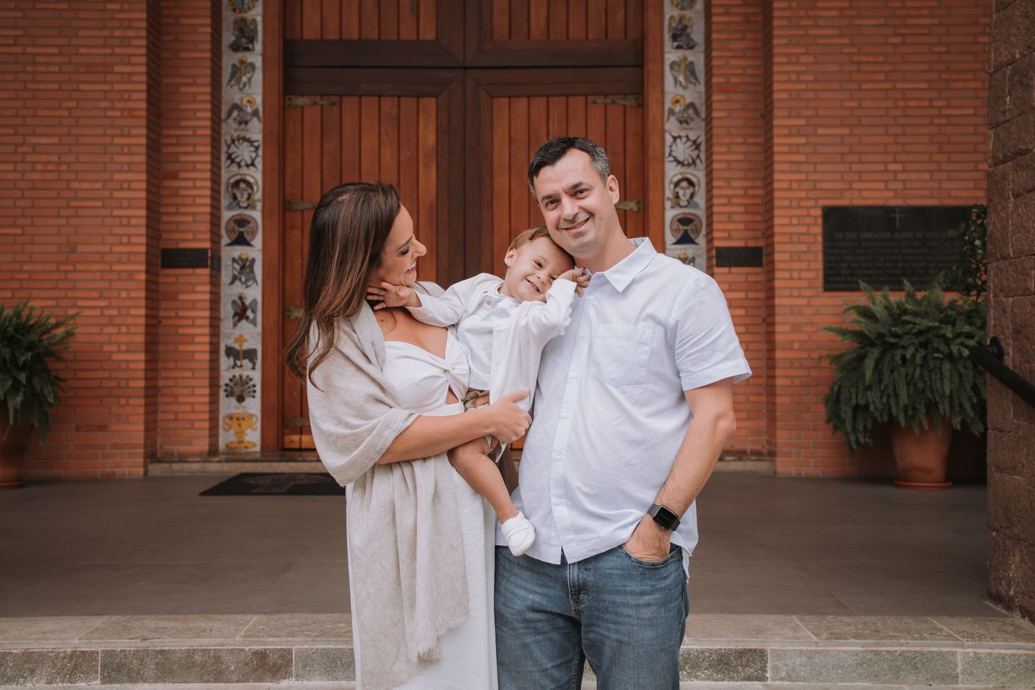 A couple shares tender moments outside a brick building with wooden doors.