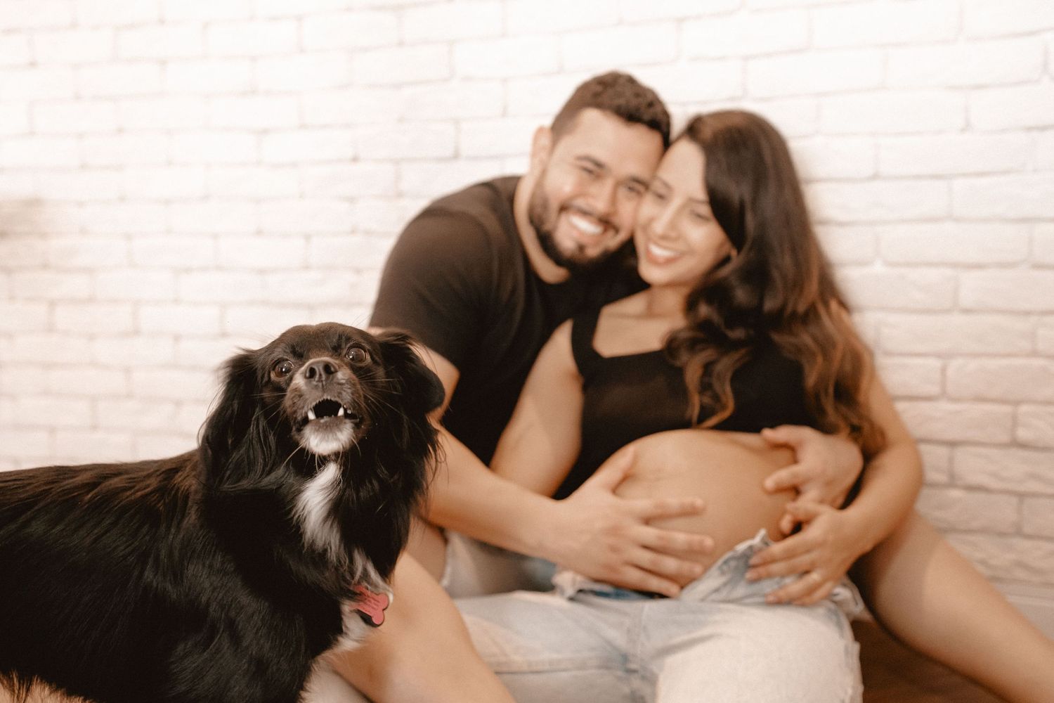 Couple sharing tender moments during indoor maternity photography session.