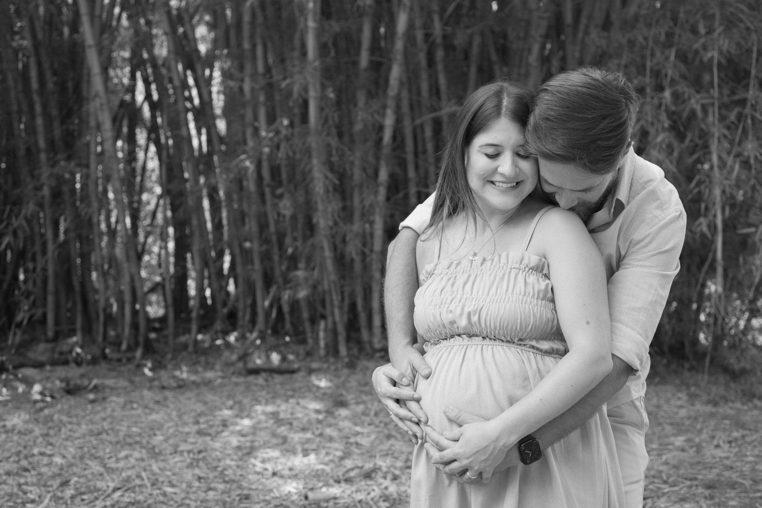 Black and white maternity portrait against bamboo forest backdrop.