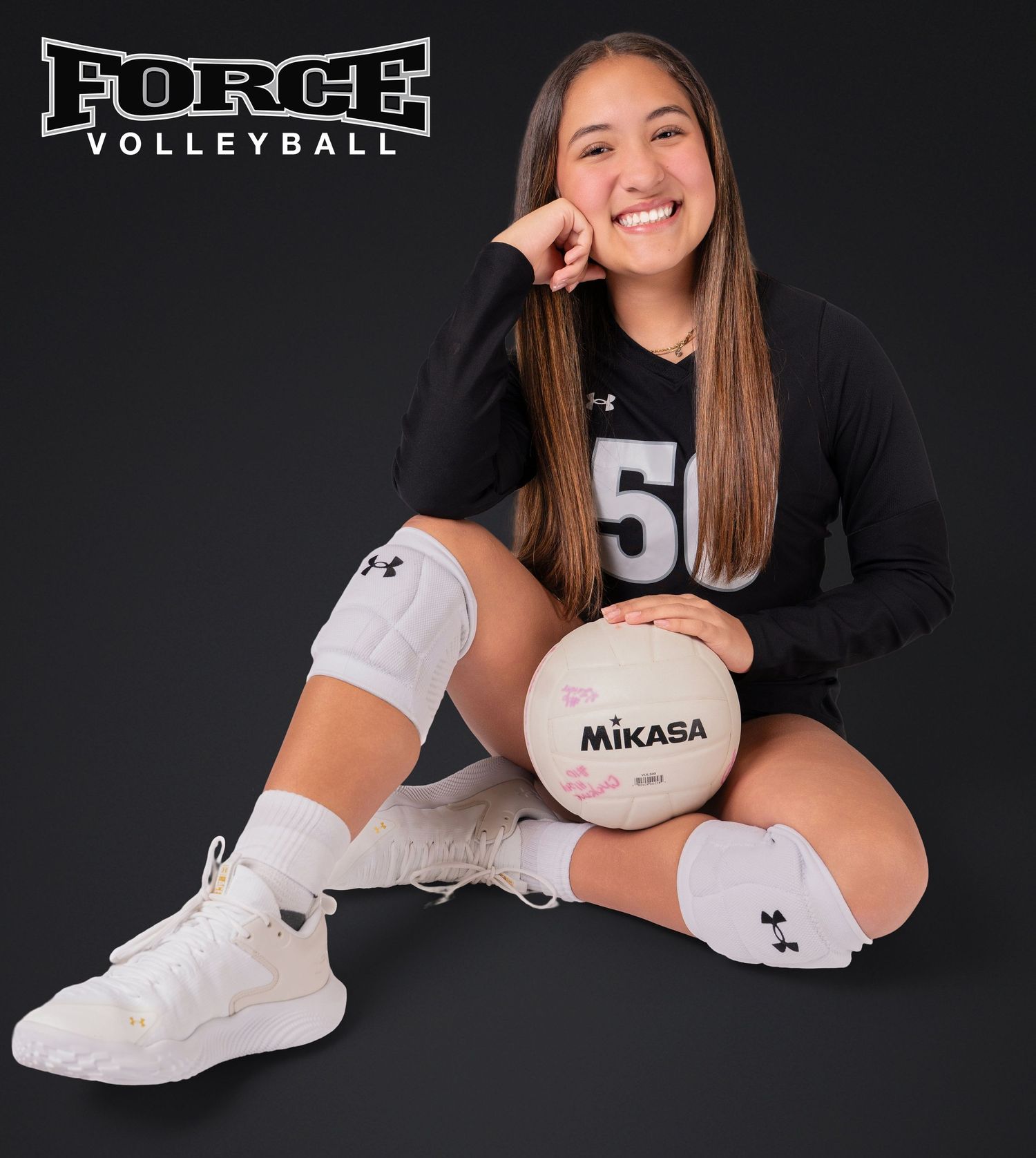 Force Volleyball player poses with Mikasa ball in studio against black backdrop.