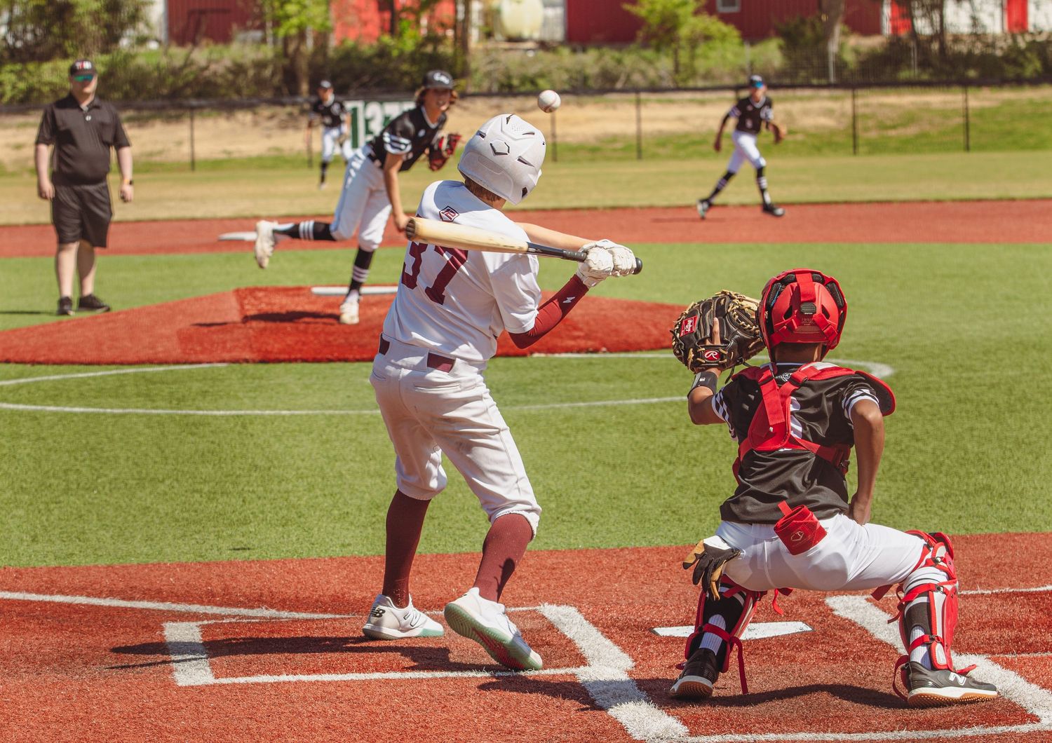 Baseball player slides into home plate during game while catcher awaits with glove ready to make the play.