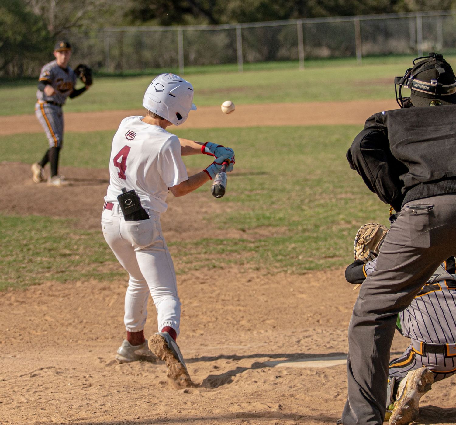 Baseball batter prepares to bunt while catcher and umpire watch from behind home plate.