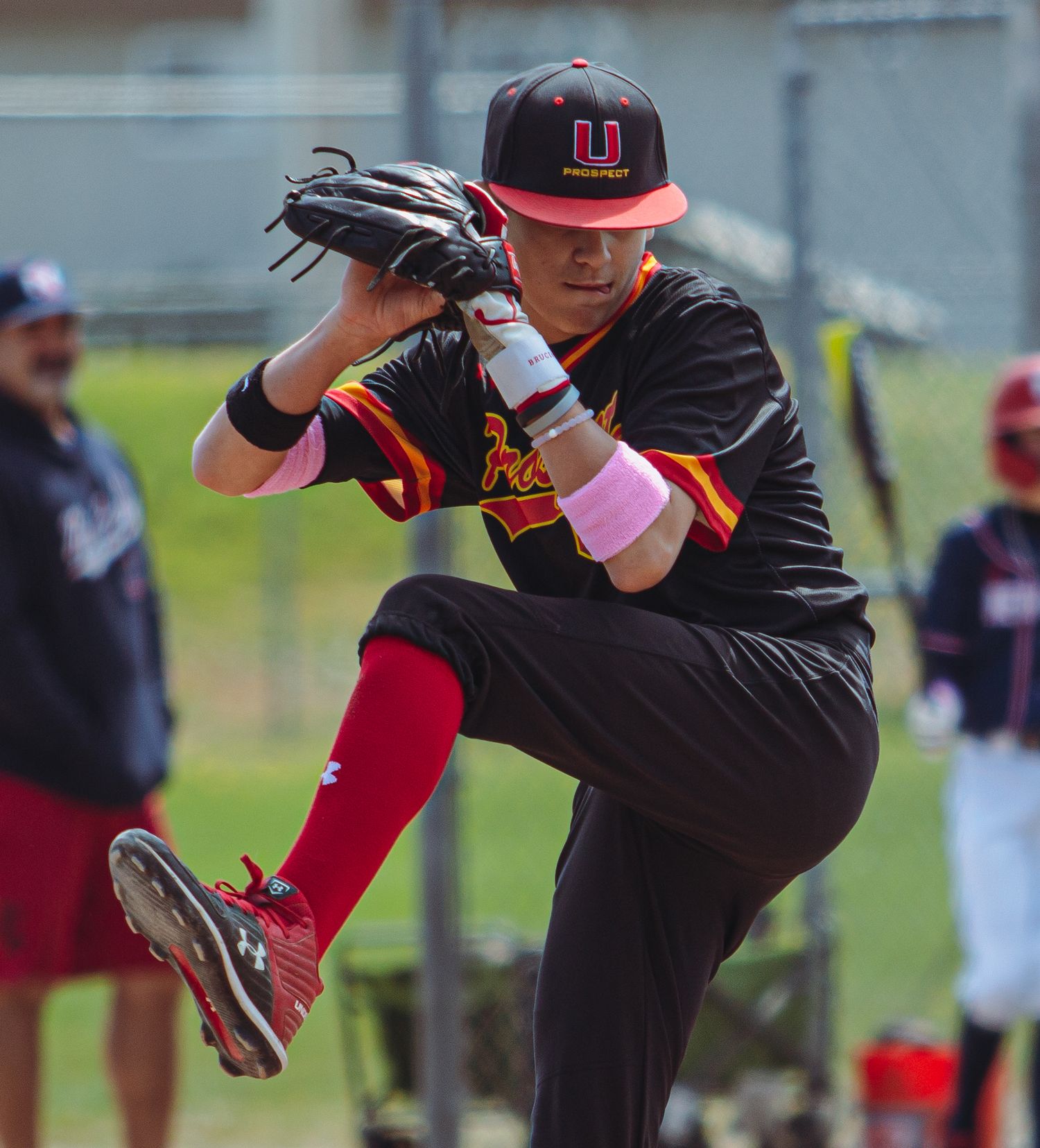 Baseball player in black uniform demonstrates proper pitching form.