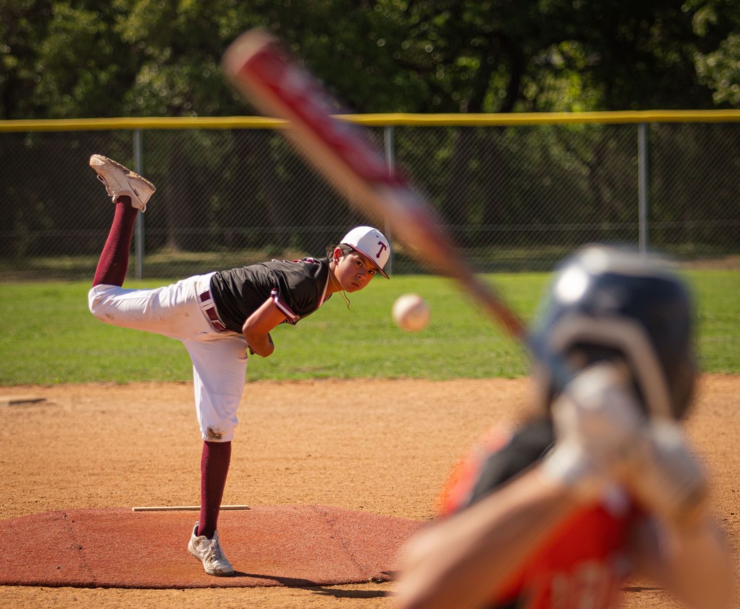 Baseball pitcher in mid-delivery motion on dirt mound during game.
