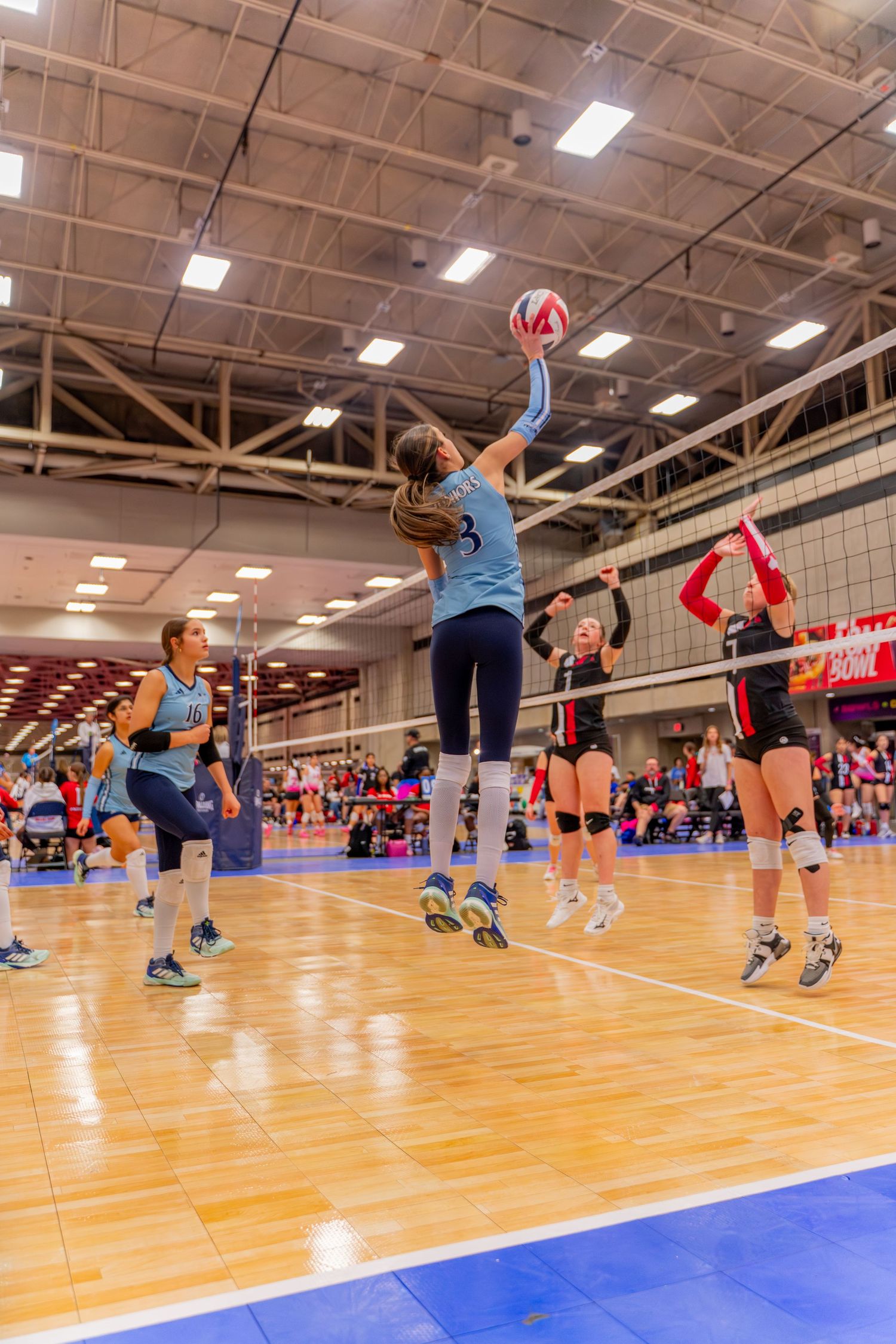 Players diving and jumping for a volleyball during an intense indoor match sequence.