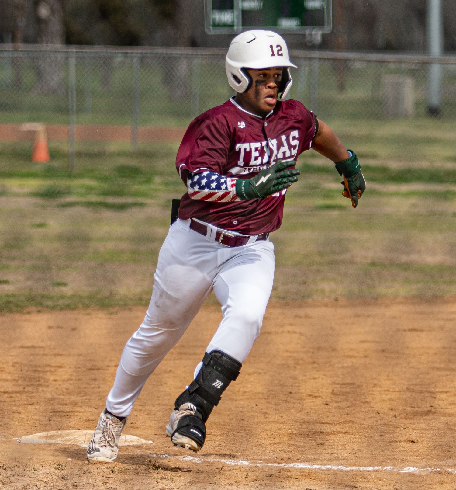 Baseball player in Texas maroon uniform running bases during game.