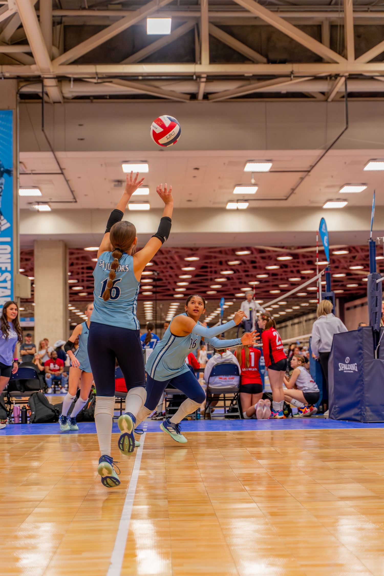 Low angle view of volleyball players diving to save the ball during an indoor match.