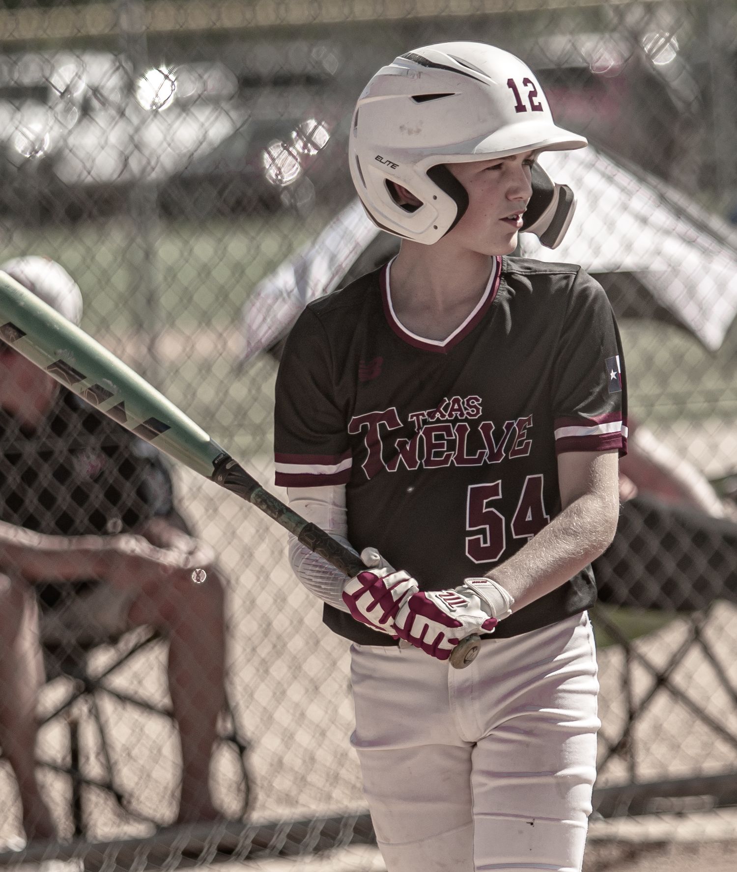 Baseball player in batting helmet holds bat while preparing to hit.
