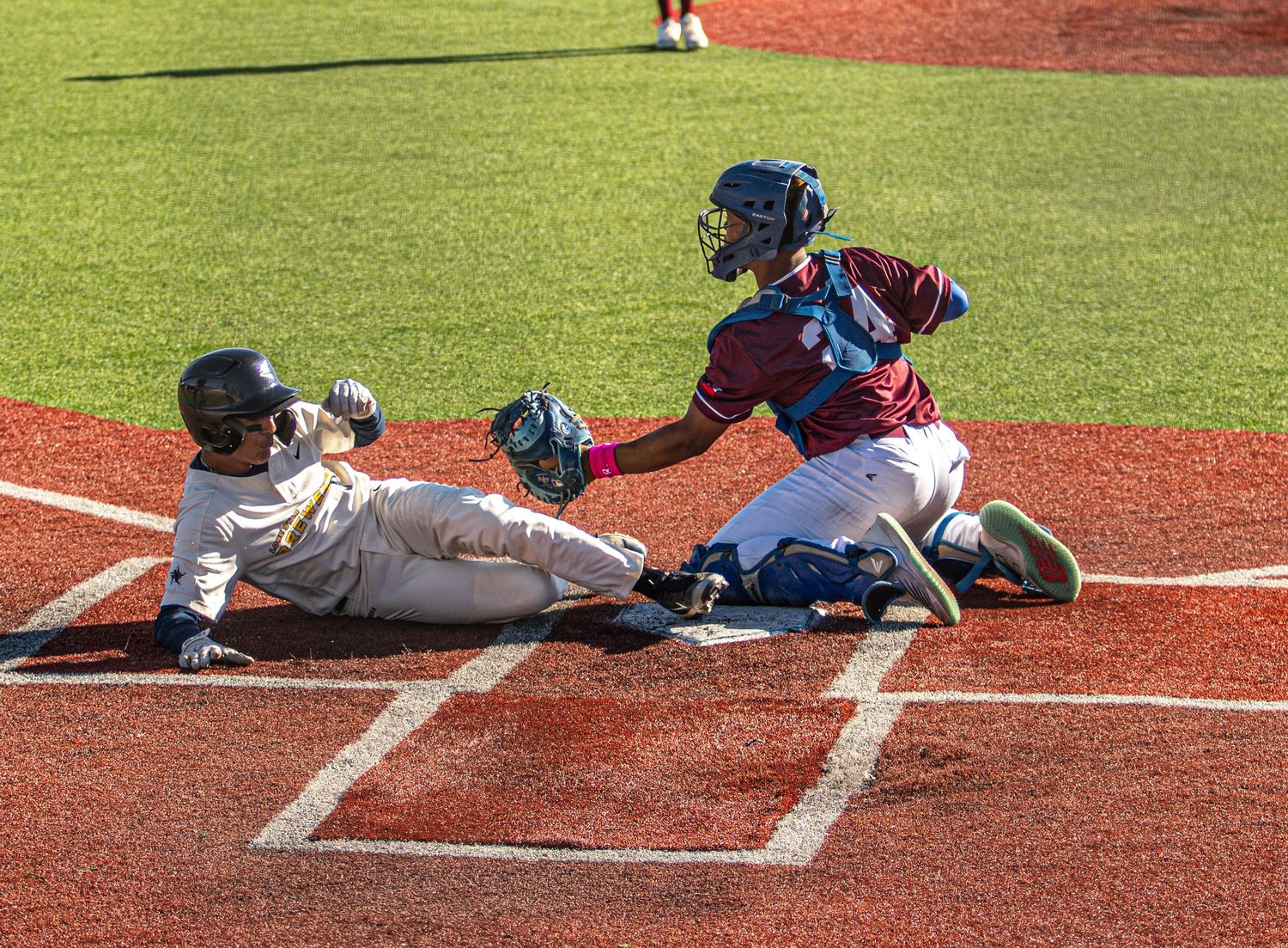 Baseball play at home plate with sliding runner and catcher attempting to make the tag.