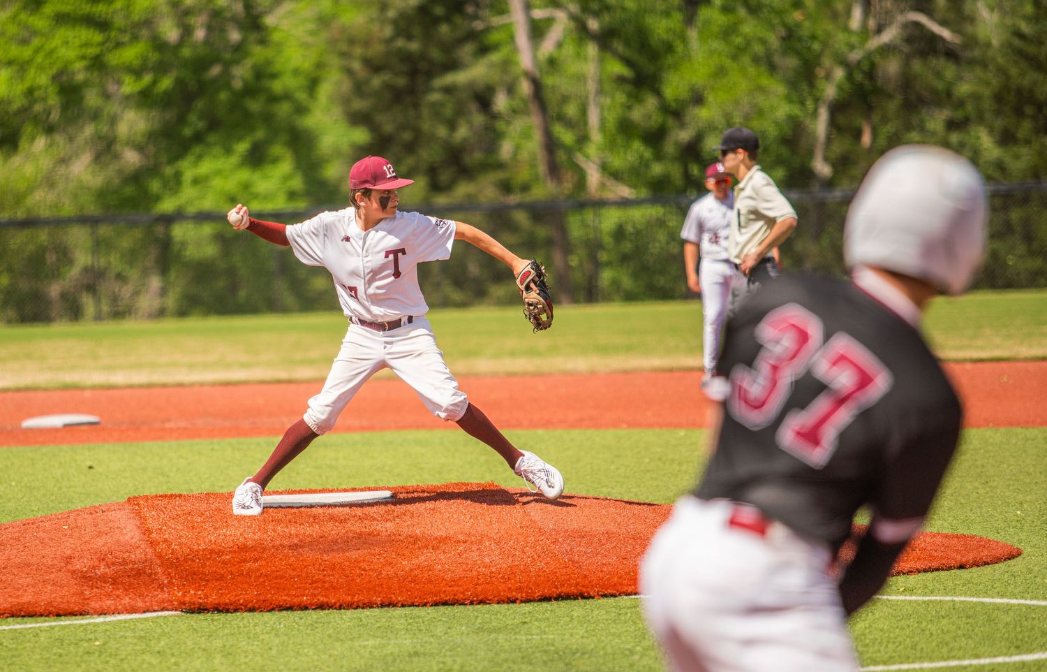 Baseball pitcher in white uniform winds up to throw from the mound during a game.