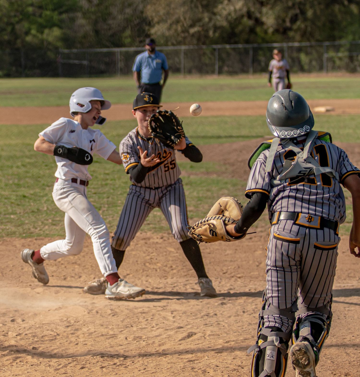 Baseball action at home plate with catcher, runner, and fielder during intense play.