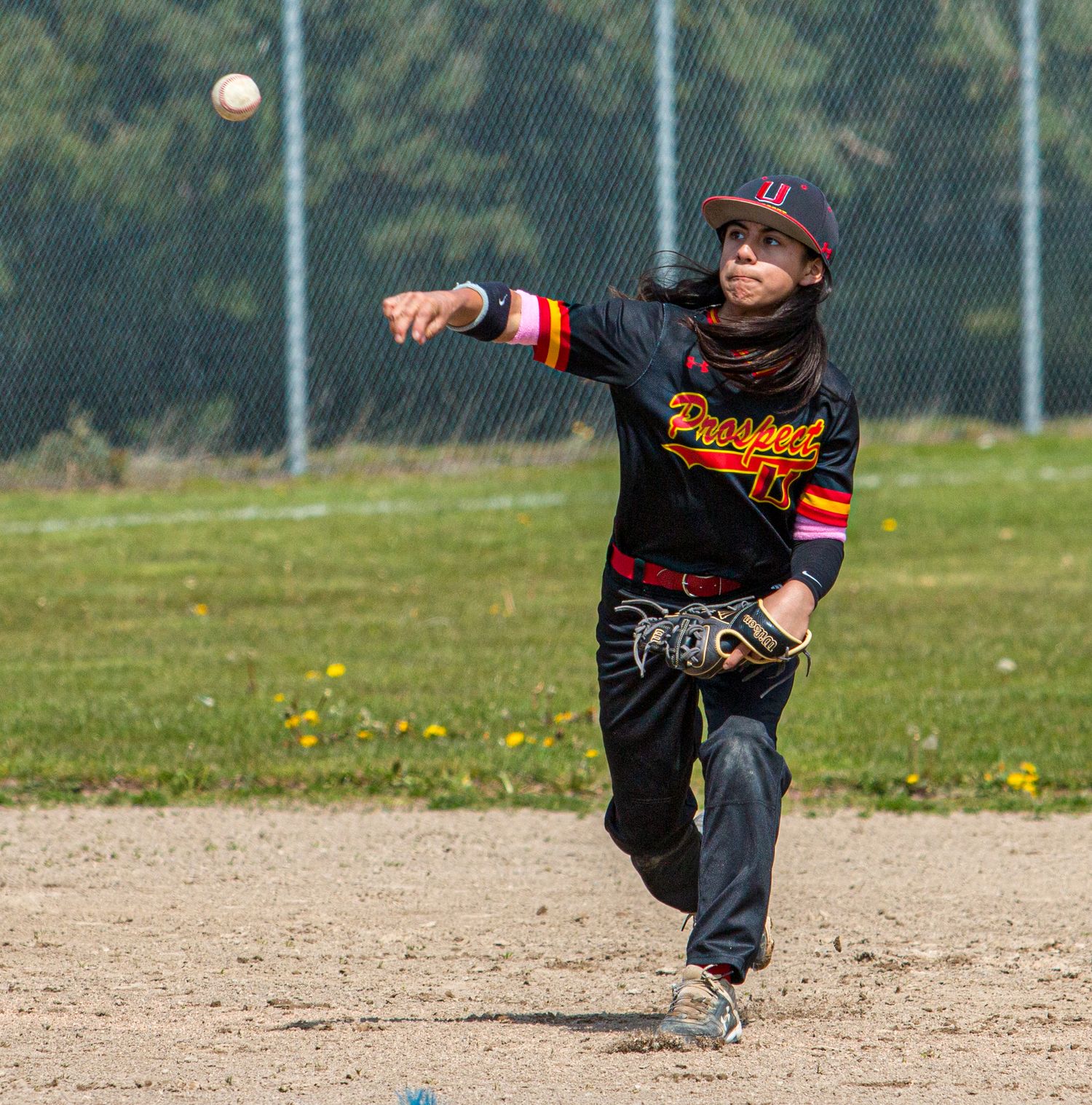 Baseball players field ground balls during practice on a dirt infield.