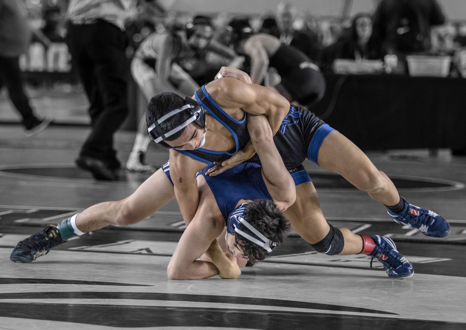 High school wrestlers grappling on mats during competitive matches.