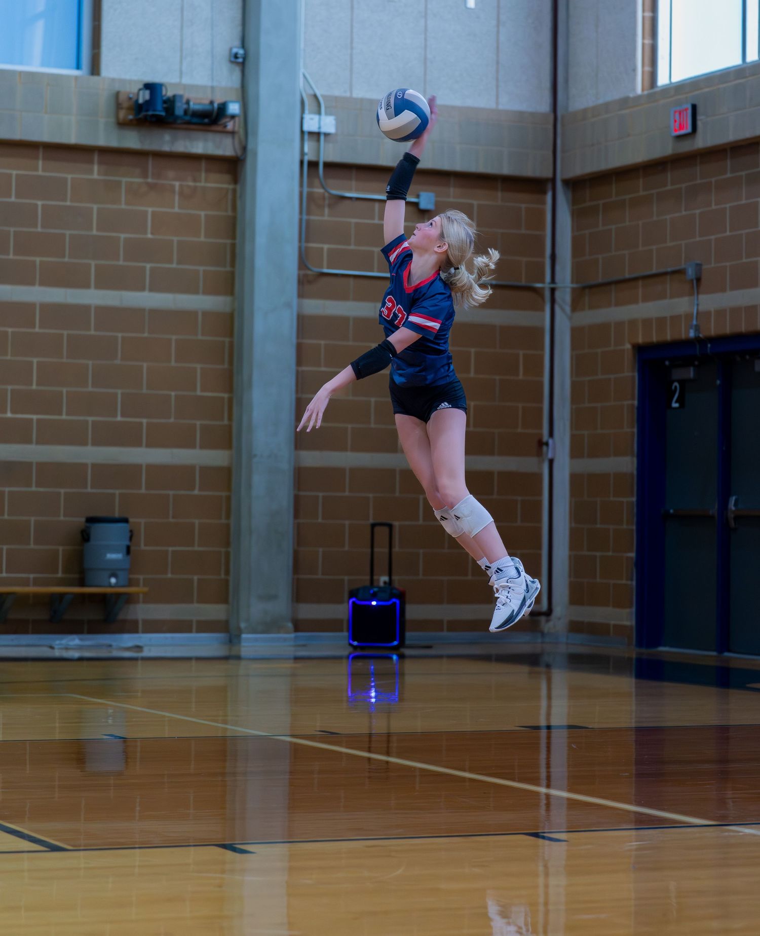 Athlete jumps to spike volleyball during indoor practice session.