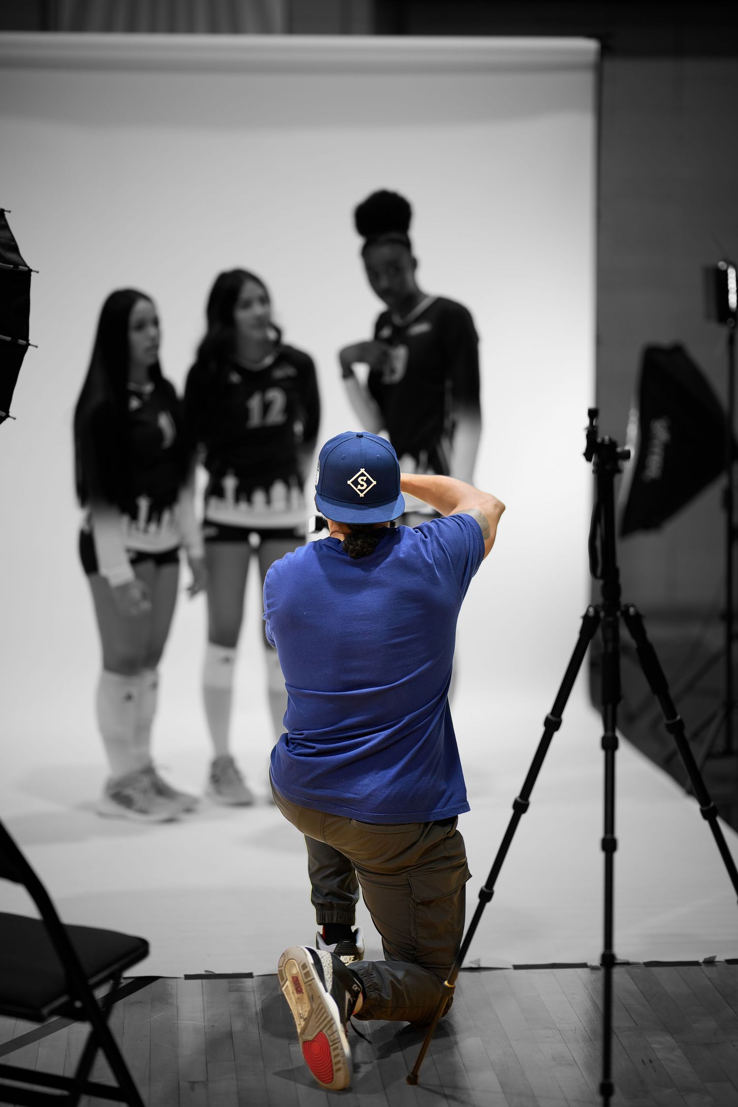 Photographer in blue shirt working in studio with lighting equipment.