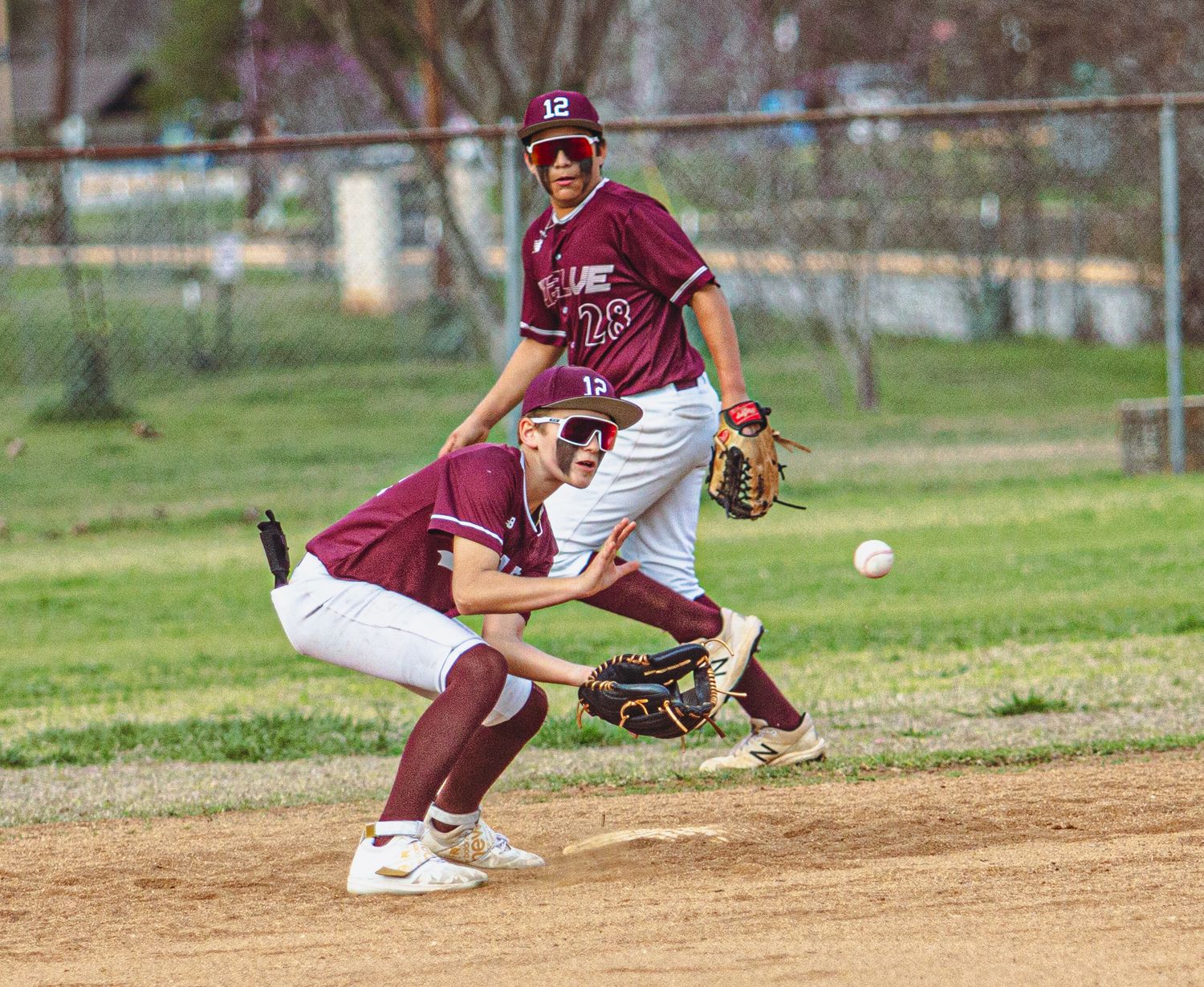 Baseball players collide during infield play as ball gets away.