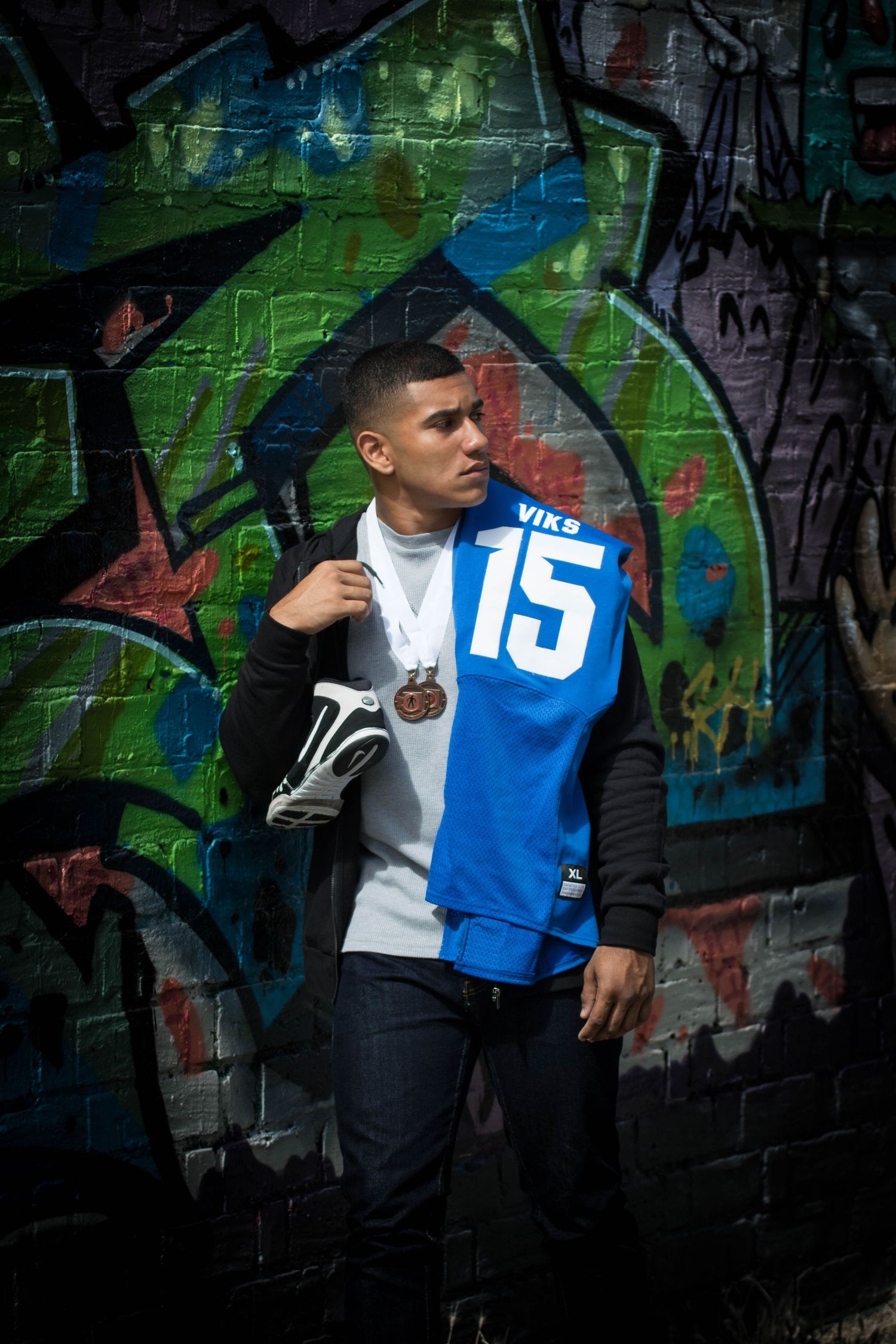 Dramatic athletic photo shoot with player posing against urban street art backdrop.