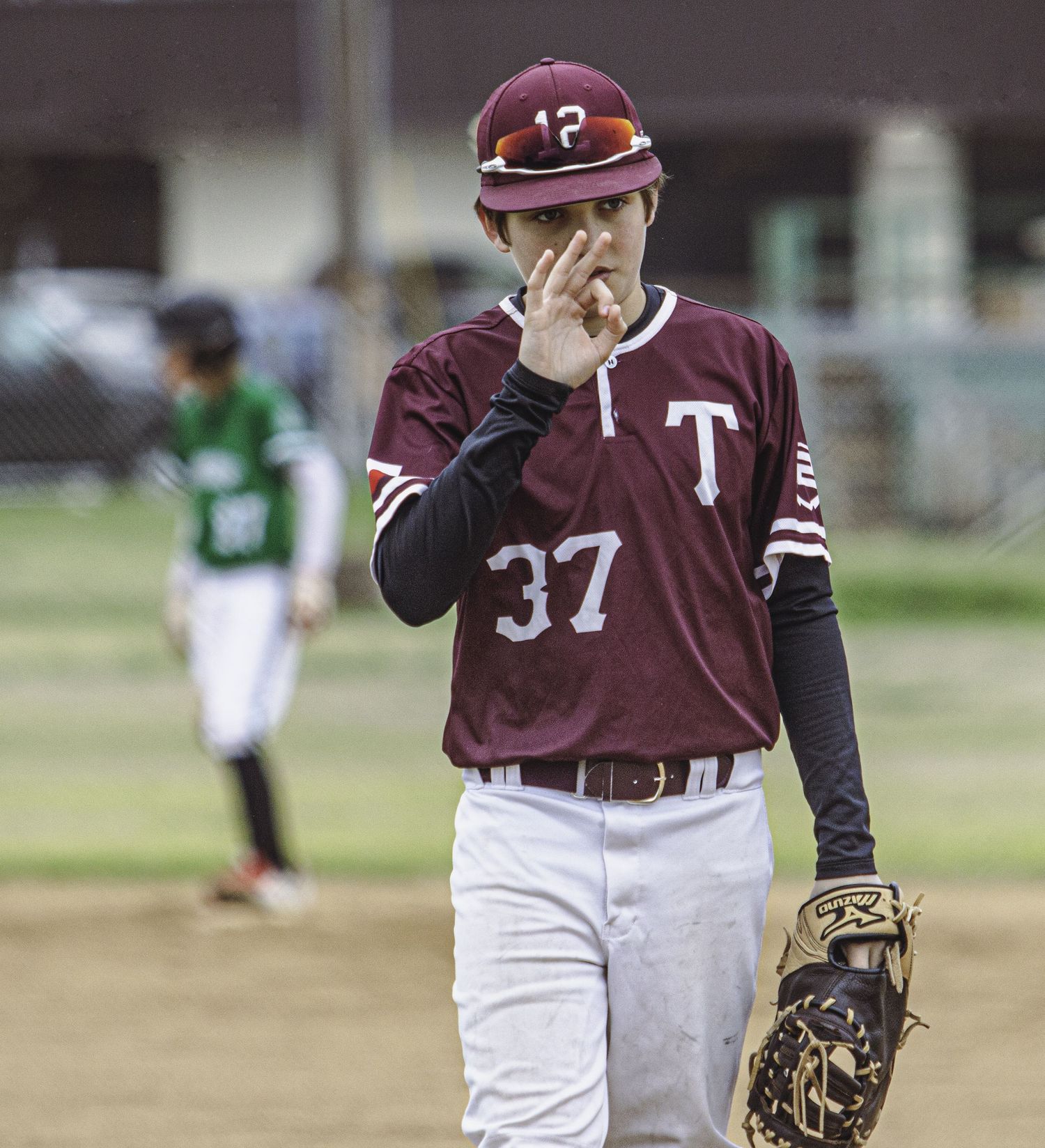 Baseball player in maroon uniform with number 37 stands on field with glove.