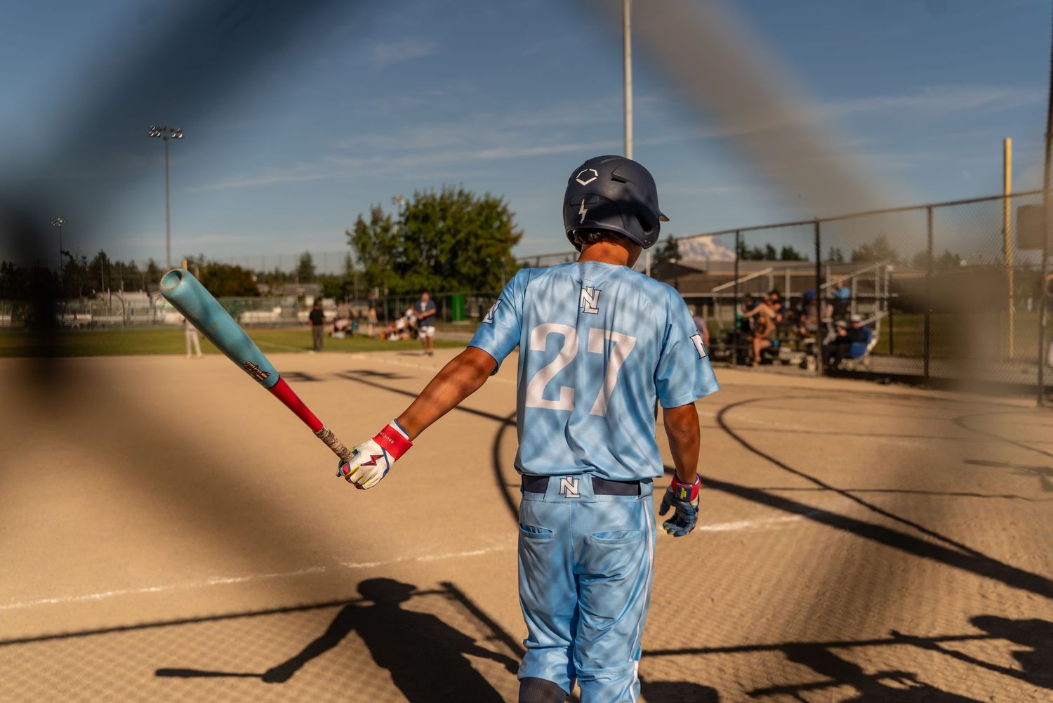 Baseball players in light blue uniforms practicing on field during evening hours.