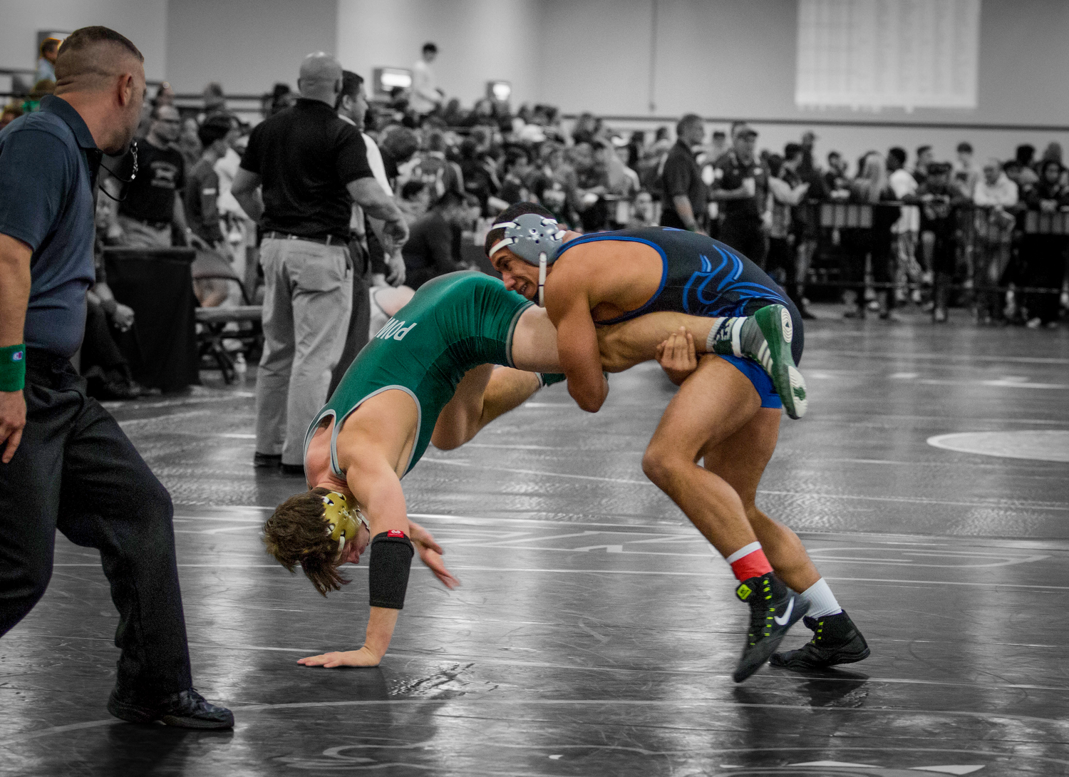 High school wrestlers engage in a competitive match on the gymnasium floor.